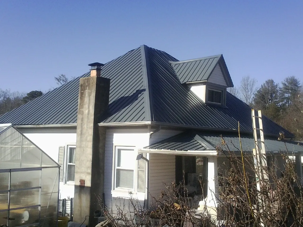 Dark blue standing seam metal roof on a white farmhouse with dormer — Slate & Tile Roof Repair by Roofing Brothers in West Berlin