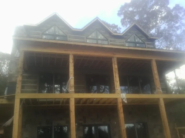 Dormers and porch framing on a large log home under construction — Roof Coating work by our crew in West Berlin