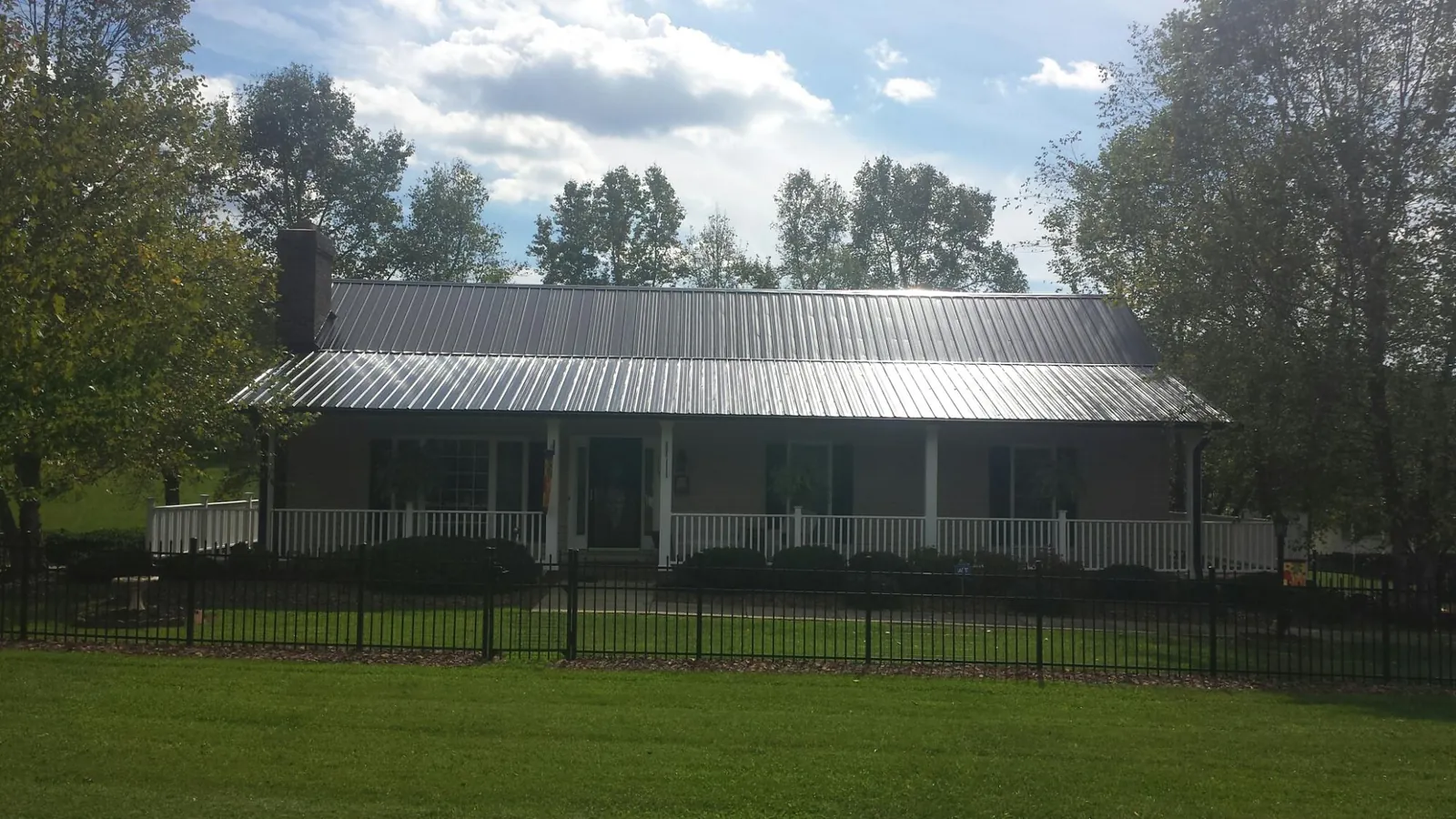 Gray metal roof on a brick ranch with a full width front porch — Gutter Guard Installation work by our crew in West Berlin