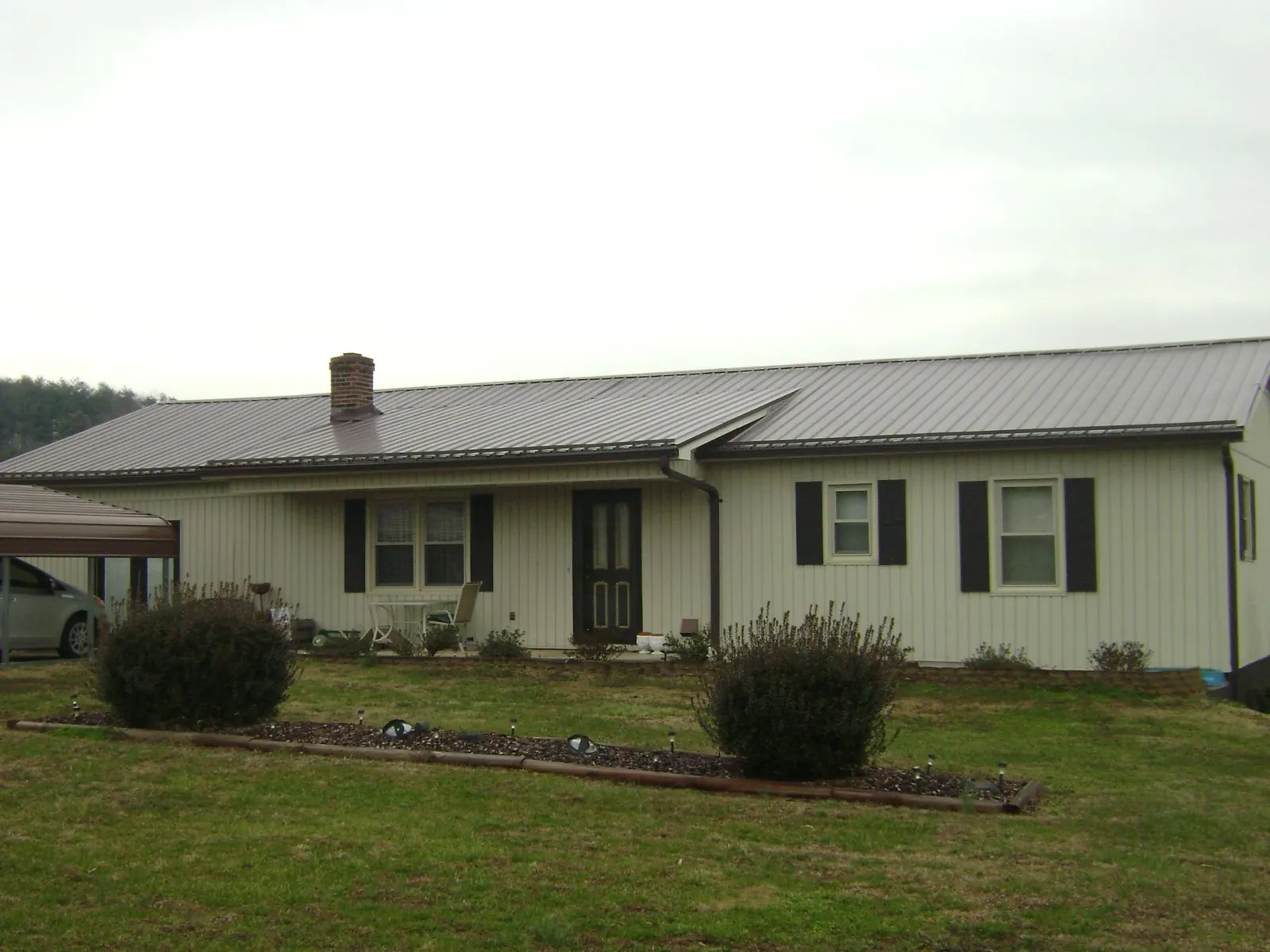 Brown metal roof on a cream sided ranch home with a brick chimney in West Berlin