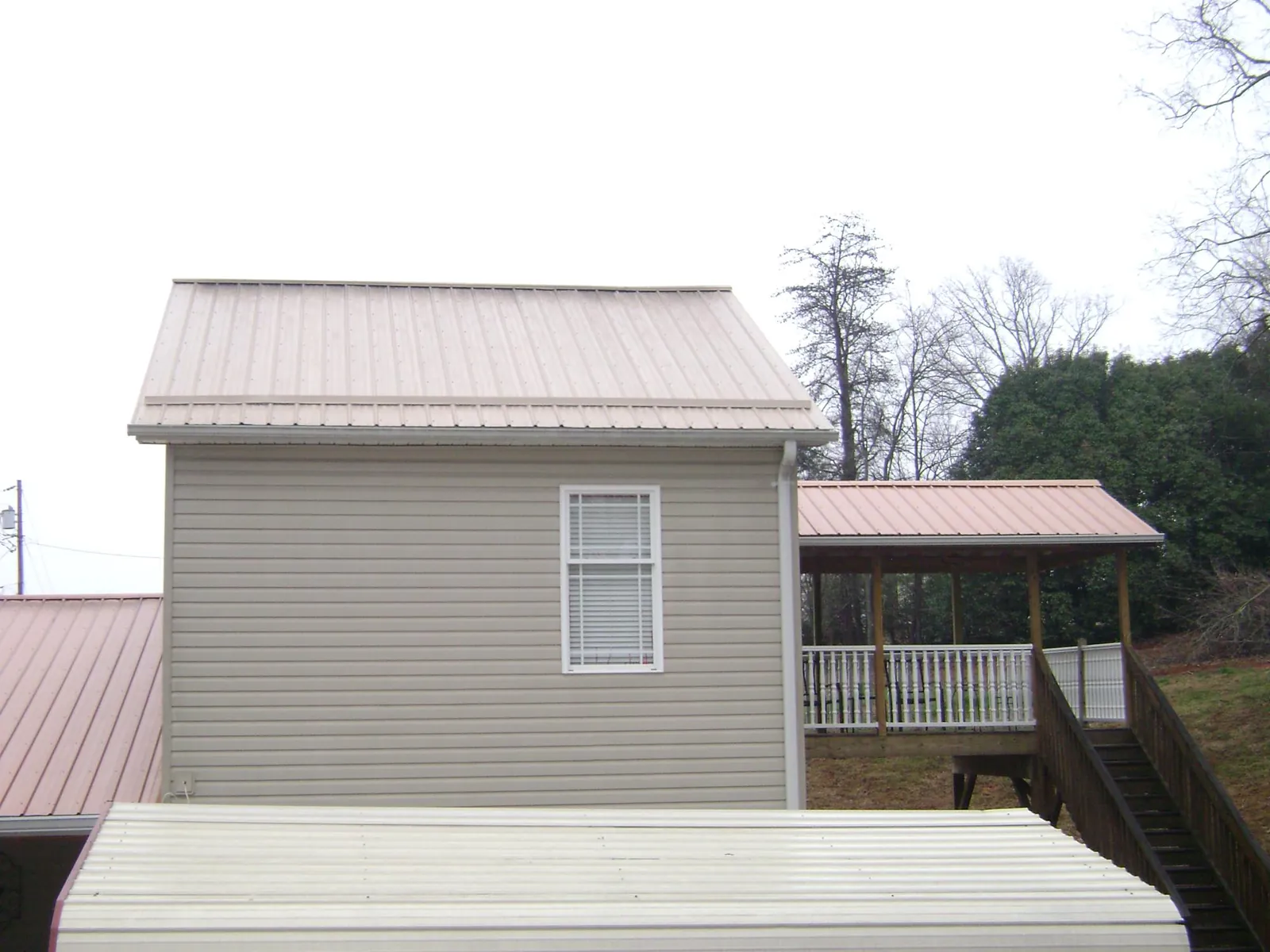 Tan metal roofs on a two story addition and attached porch, from a Roof Replacement job in West Berlin