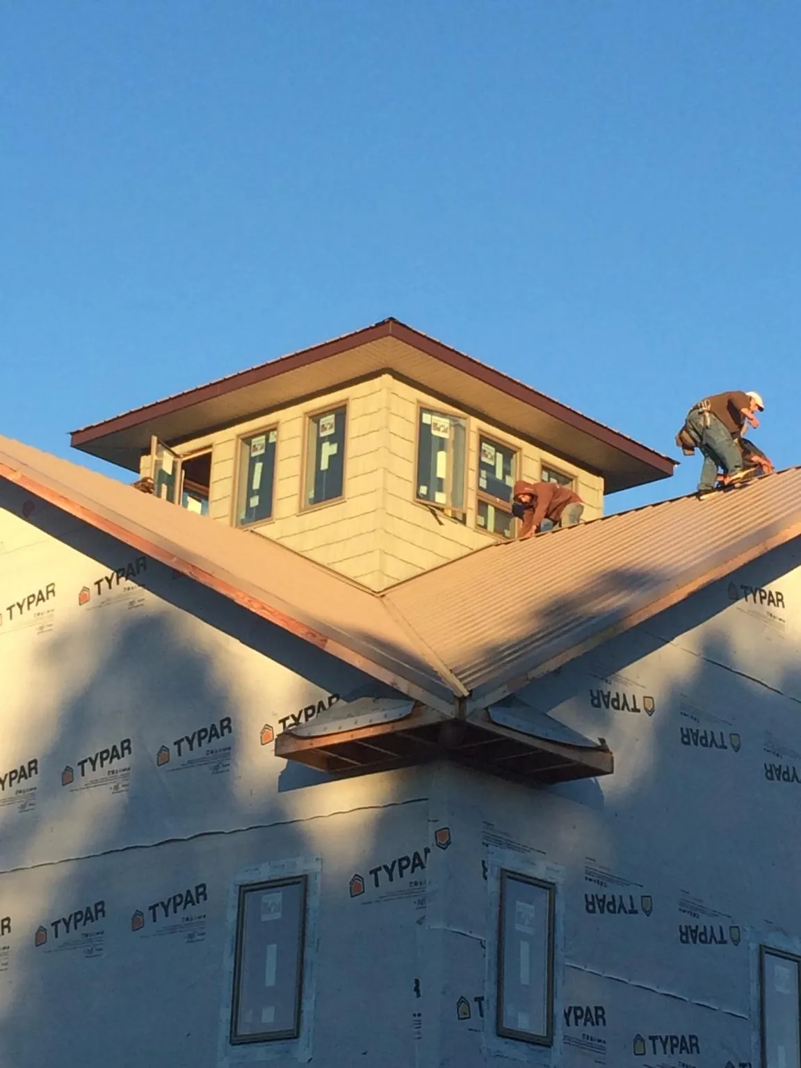 Roofers working around a rooftop cupola on a new metal roof at sunset — Roof Waterproofing in West Berlin by Roofing Brothers